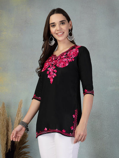 Black embroidered rayon kurti with pink floral design worn with white pants.