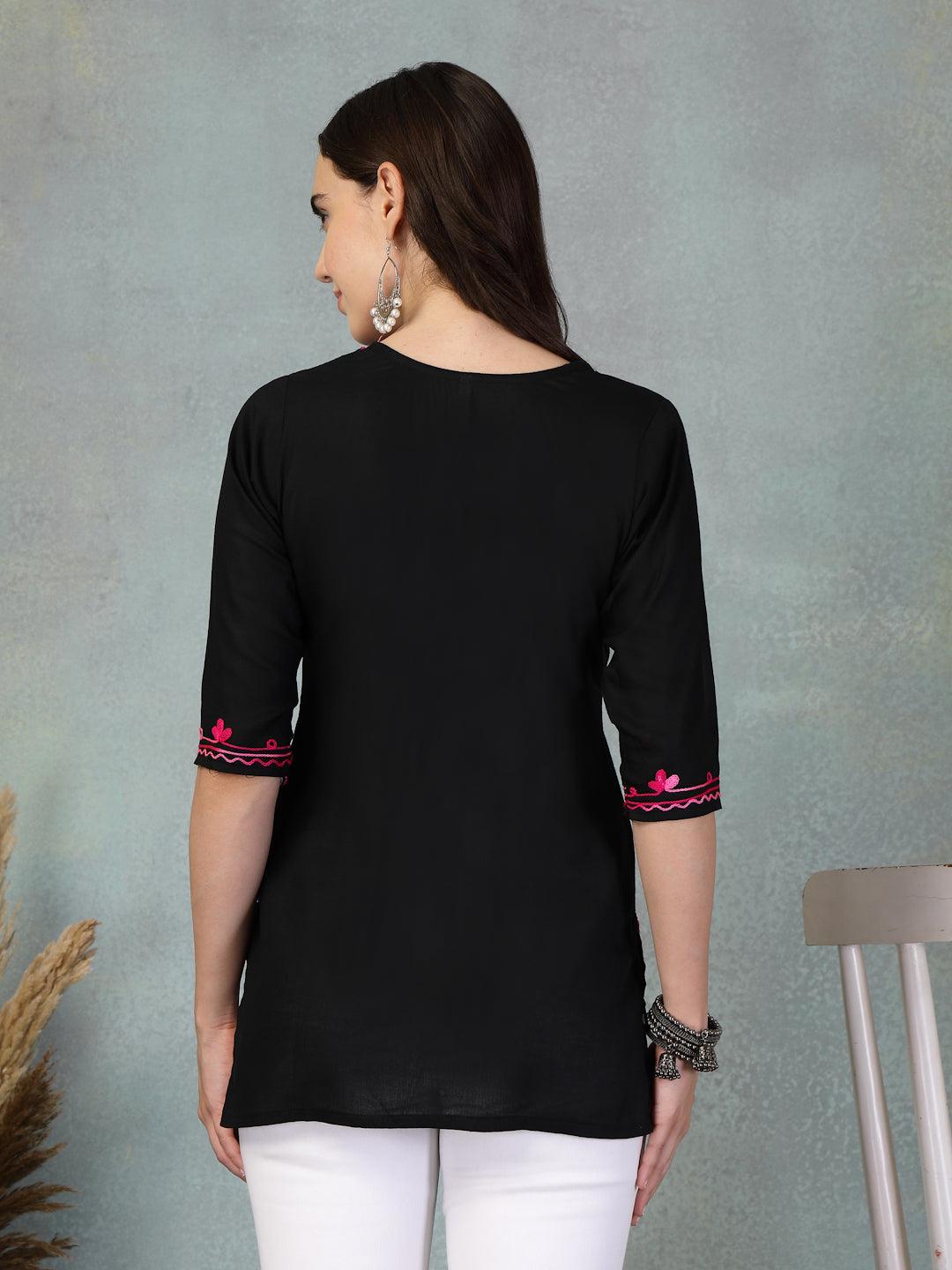 Back view of a black embroidered rayon kurti with pink embroidery on sleeves worn with white pants