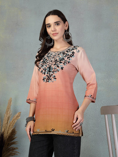 Woman wearing peach embroidered rayon kurti with black floral embroidery, paired with black pants