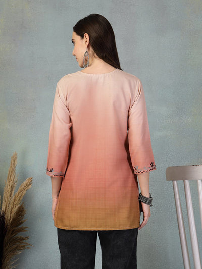 Back view of a woman wearing a peach embroidered rayon kurti with three-quarter sleeves and black pants against a gray background.
