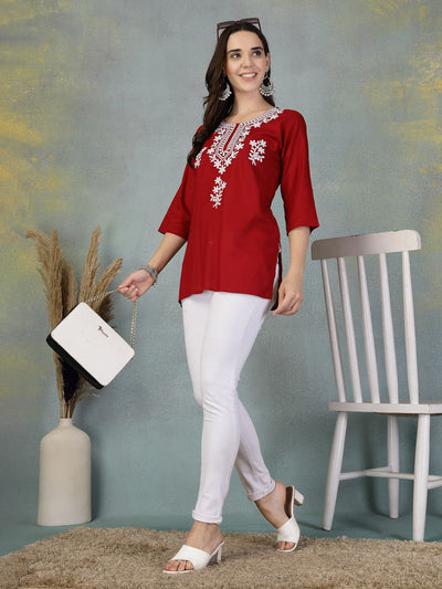 Maroon embroidered rayon kurti worn with white leggings and heels by a smiling woman in a casual setting