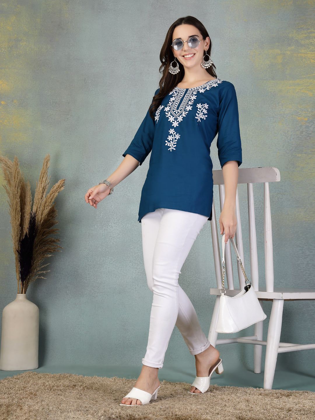 Peacock blue embroidered rayon kurti with white floral designs paired with white leggings and accessories