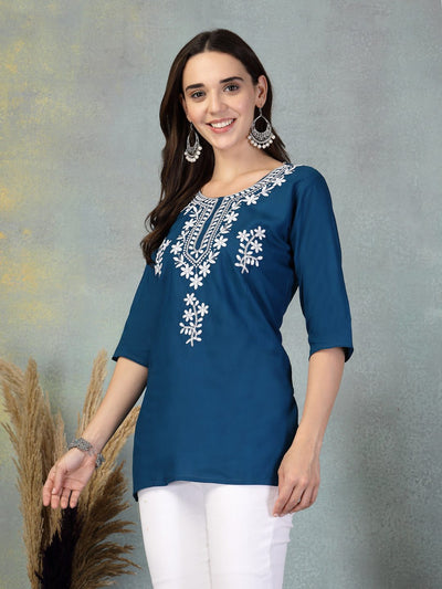 Peacock blue embroidered rayon kurti with white floral design and three-quarter sleeves worn with white pants