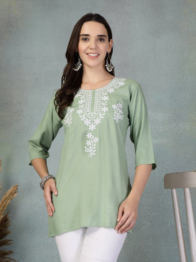 Pista green embroidered rayon kurti with white floral embroidery, three-quarter sleeves, worn with white pants.