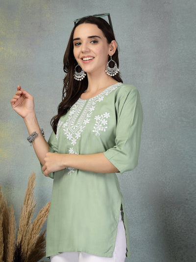 Pista green embroidered rayon kurti with white floral patterns and three-quarter sleeves worn with white leggings