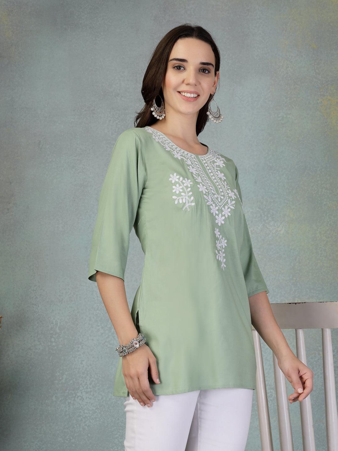 Pista green embroidered rayon kurti with white floral embroidery and three-quarter sleeves worn with white pants.