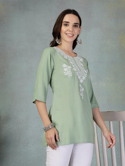 Pista green embroidered rayon kurti with white floral embroidery and three-quarter sleeves worn with white pants.
