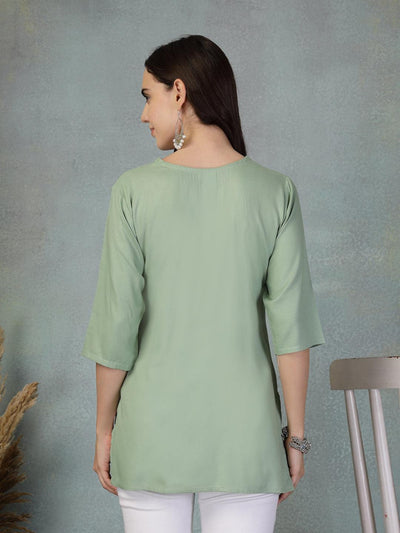 Back view of a woman wearing pista green embroidered rayon kurti with three-quarter sleeves and paired with white pants