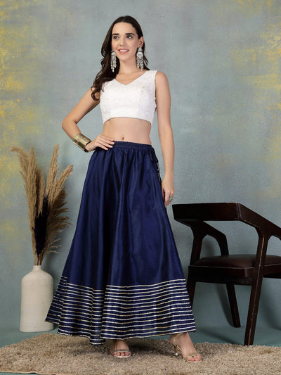 Navy blue flared Chanderi silk skirt with intricate Gota Patti work modeled with white crop top and silver accessories