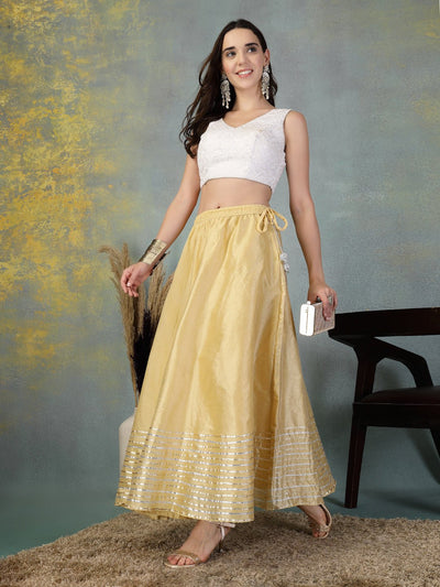 Woman wearing fawn Gota Patti Chanderi silk flared skirt with white crop top and silver accessories
