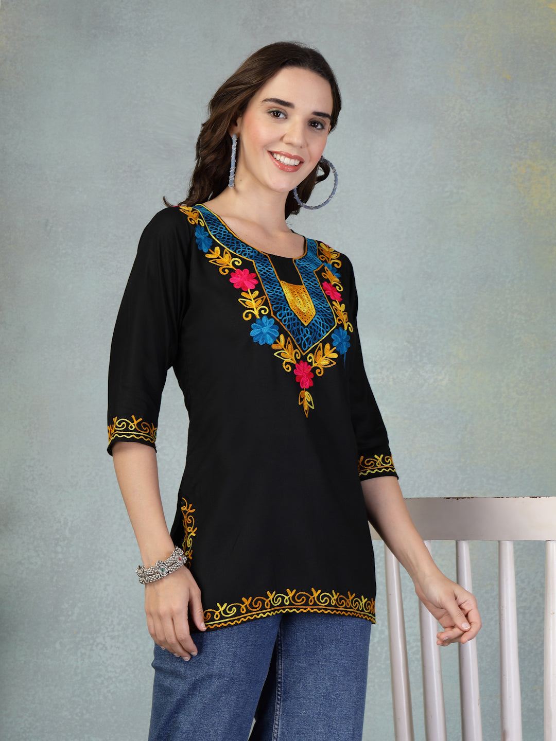 Black embroidered rayon kurti with colorful floral embroidery, worn with jeans, featuring three-quarter sleeves and intricate detailing.