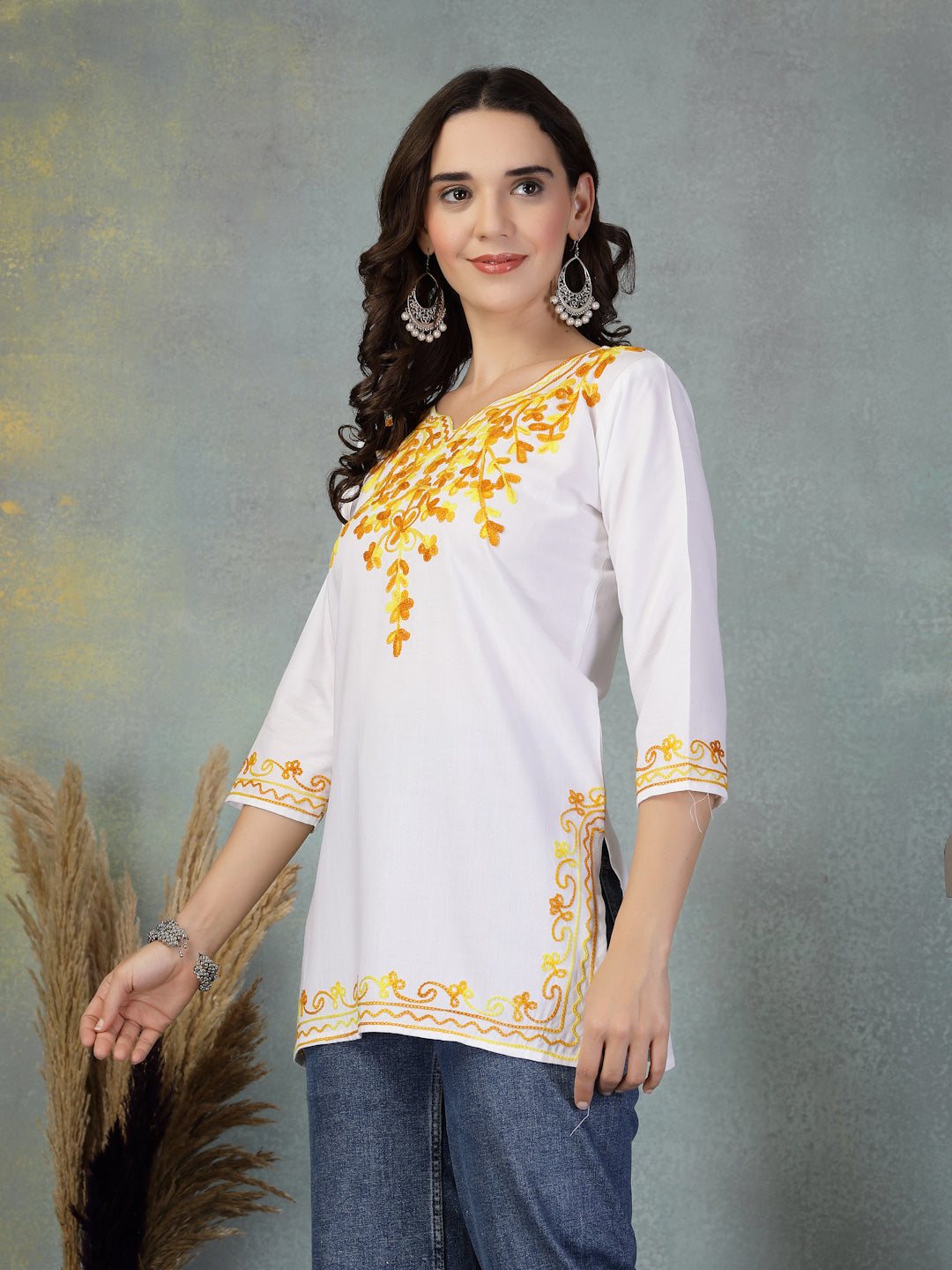 White embroidered rayon kurti with yellow floral embroidery, three-quarter sleeves, and side slits paired with blue jeans