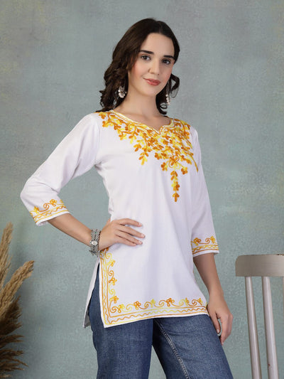 White embroidered rayon kurti with yellow floral embroidery, three-quarter sleeves, and side slits paired with jeans