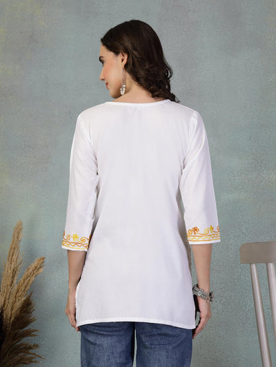 Back view of white embroidered rayon kurti with three-quarter sleeves and yellow embroidery on cuffs paired with blue jeans
