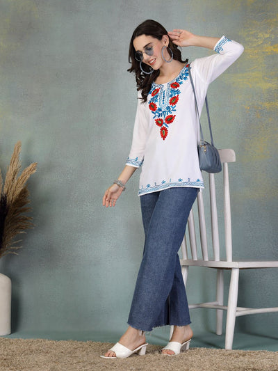 White embroidered rayon kurti with floral designs paired with blue jeans and white heels