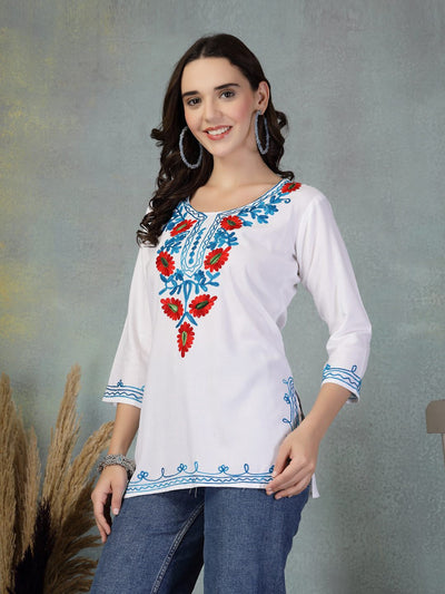 White embroidered rayon kurti with blue and red floral designs worn with jeans