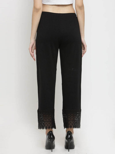 Black viscose lace palazzo pants with ankle-length design, worn with heels.