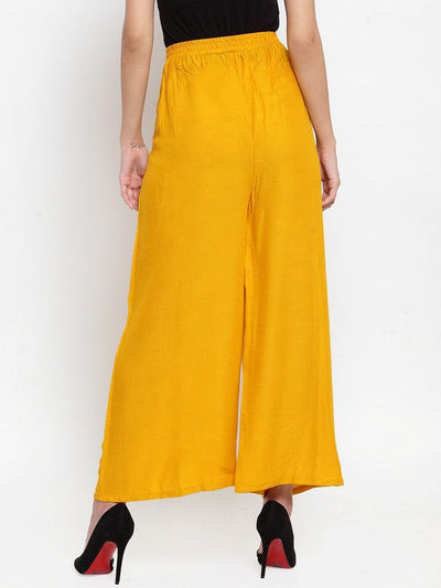 Mustard wide leg solid palazzo pants with tie knot design, worn by woman.