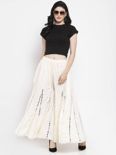 Cream flared embellished Sharara in soft Rayon fabric worn by a model with sunglasses and a black top.