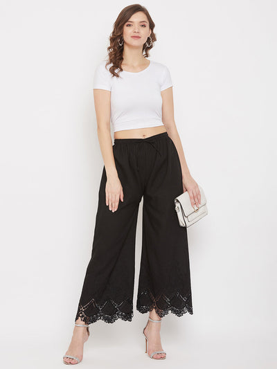 Black straight embroidered palazzo with elasticated waistband, worn with a white top and heels.
