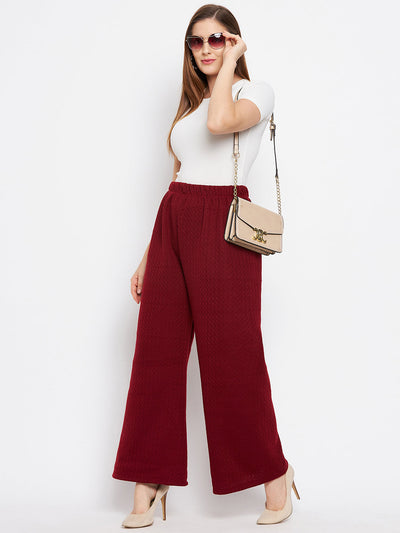 Maroon solid woolen palazzo pants styled with a white top and beige handbag.
