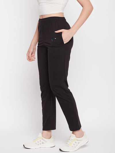 Black solid mid rise cotton track pants with elasticated waistband, drawstring closure, concealed zip pocket, and open pocket.