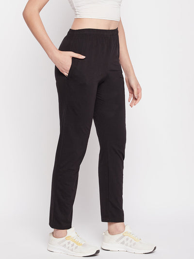 Black solid mid rise cotton track pants with elastic waistband and pockets.