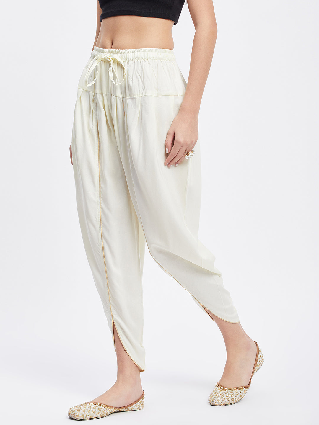 Cream solid rayon tulip pant with elastic waistband and drawstring.
