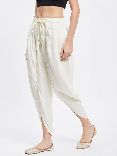 Cream solid rayon tulip pant with elastic waistband and drawstring.