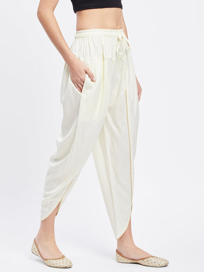 Cream solid rayon tulip pant with elasticated waistband and drawstring.