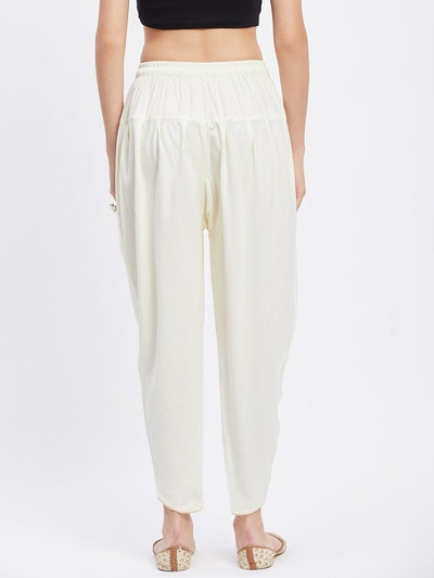 Cream solid rayon tulip pant with elasticated waistband and drawstring.
