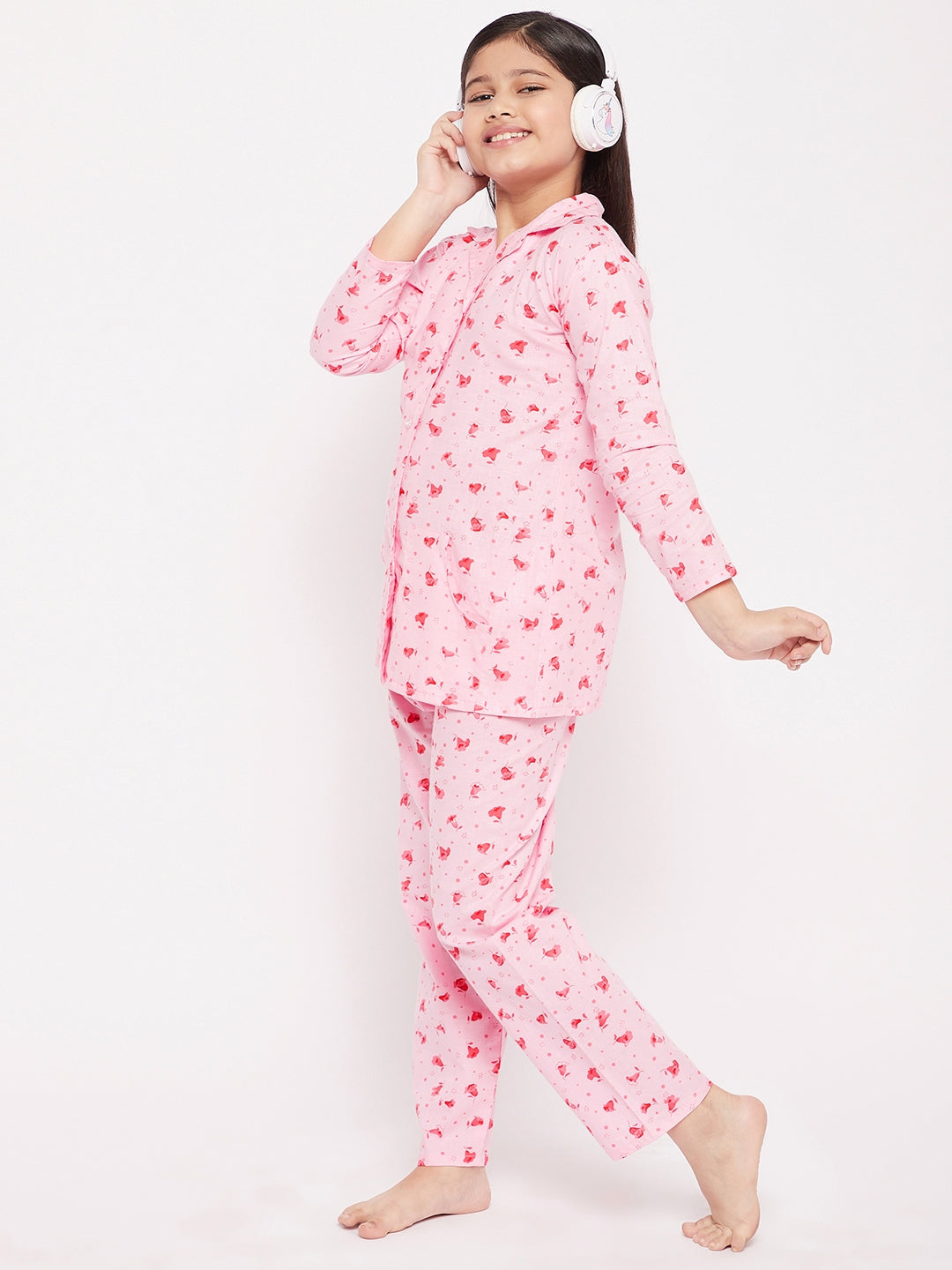 Girl wearing pink flower print cotton nightsuit standing against a white background.