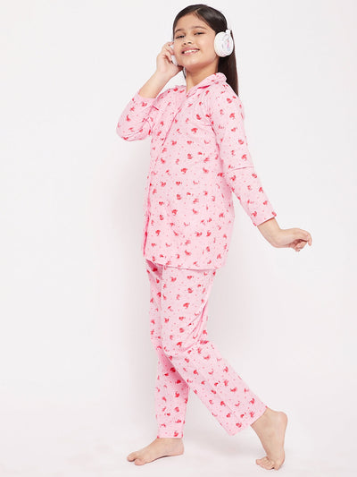 Girl wearing pink flower print cotton nightsuit standing against a white background.